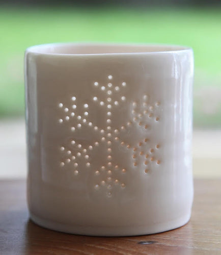 Porcelain ceramic tealight candle holder, glazed in a natural glossy glaze, and pierced with a snowflake design. Christmas gift. Decoration.