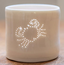 Load image into Gallery viewer, A porcelain tealight holder, with a crab design pierced into it with tiny holes that let the light shine through. This ceramic candle votive is perfect for seaside holidays 
