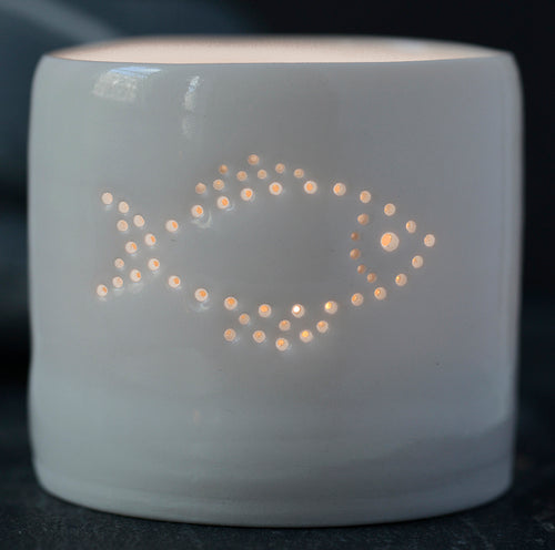 Part of the seaside collection, this porcelain tealight holder features a fish design. This ceramic candle holder is pierced with tiny holes to create a natural glossy glow.