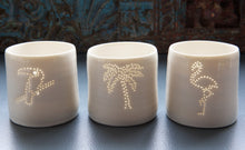 Load image into Gallery viewer, Paired with the palm tree and toucan, a tropical party present. This ceramic candle votive features a design of a flamingo. Holiday candle, this porcelain tealight holder glows from within once a candle is lit.
